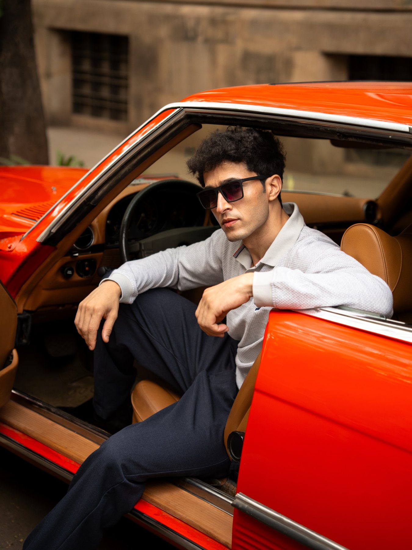 Raff seated beside the red car, with his hands and the car visible